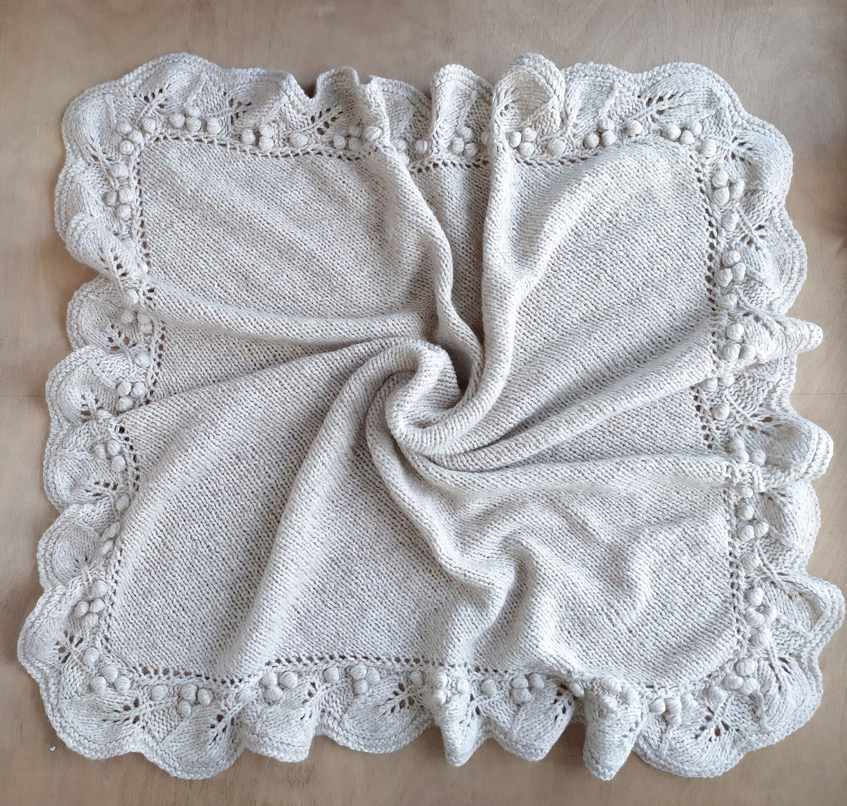 Close view of the blanket's knitted texture and lace edging